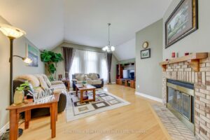 Large family room with vaulted ceiling, hardwood flooring, gas fireplace and oversized windows.