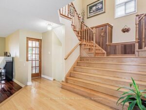 Main foyer with hardwood staircase leading to upper level and adjacent living room entrance.