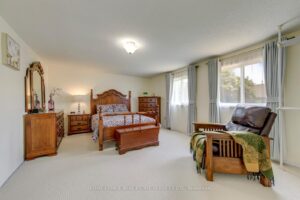 Spacious primary bedroom with large windows, neutral décor and ample floor space.