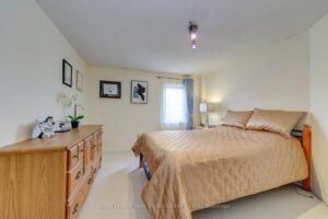 Secondary bedroom with neutral carpeting, large window and double bed.
