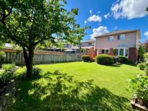 Rear exterior of 3364 Ingram Rd. showcasing the backyard, spacious deck, landscaped lawn and mature trees.