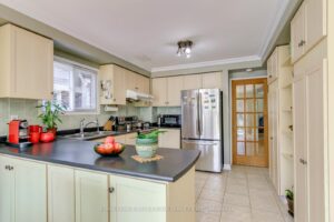 Spacious eat-in kitchen with centre peninsula, stainless steel refrigerator and ample cabinetry.