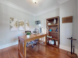 Private home office with hardwood flooring, built-in shelving, and French doors.