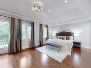 Spacious primary bedroom with tray ceiling, hardwood flooring, and large windows.