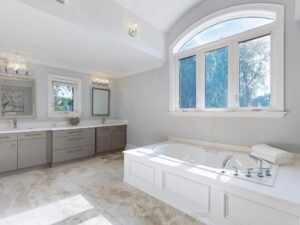Spa-inspired primary ensuite with freestanding tub, double vanity, and oversized window.