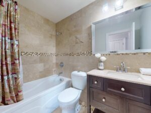 Four-piece bathroom with granite vanity, tiled walls, and bathtub-shower combination.