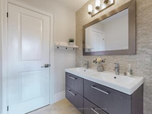 Modern bathroom with quartz vanity, framed mirror, and contemporary fixtures.