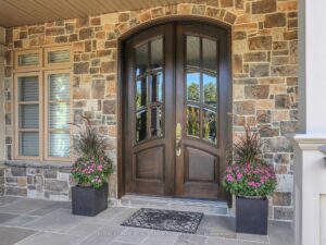 Grand covered front entrance with stone façade, double doors, and elegant architectural details.