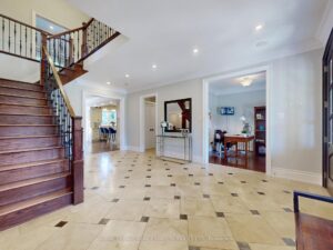 Grand foyer with sweeping staircase, polished tile flooring, and open-concept layout.