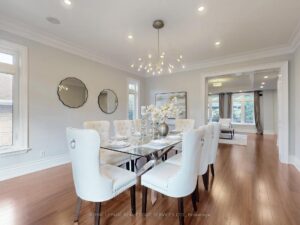 Formal dining room with elegant chandelier, hardwood flooring, and large picture windows.