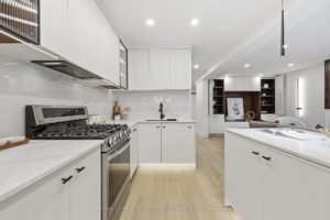 Open-concept kitchen overlooking the living room with custom cabinetry, quartz surfaces and built-in feature wall.