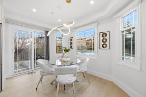 Bright breakfast area with designer lighting, glass dining table, large windows and walkout to the backyard patio.