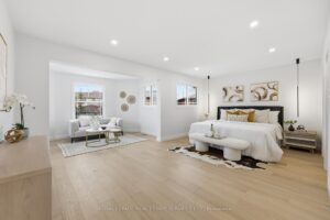 Spacious primary bedroom with sitting area, wide-plank hardwood floors and oversized layout filled with natural light.
