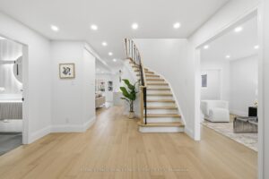 Bright front foyer featuring wide-plank hardwood floors, elegant curved staircase and open-concept layout.