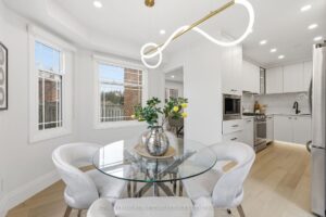 Sunny breakfast nook with designer lighting, large windows and views into the modern white kitchen.