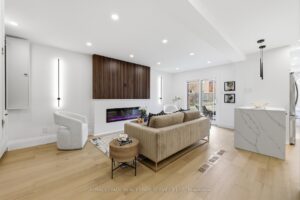 Contemporary family room featuring a linear fireplace, wood accent wall, quartz island and open-concept design.