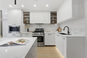 Designer white kitchen with quartz countertops, waterfall island, fluted cabinetry and stainless steel appliances.