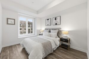 Bright primary bedroom featuring a large window, contemporary finishes and plush upholstered headboard.