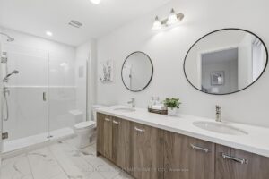 Luxury ensuite bathroom with double vanity, quartz countertop, glass walk-in shower and modern fixtures.