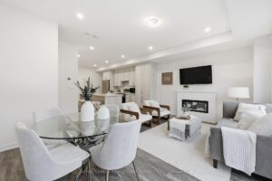 Bright open-concept living and dining area with fireplace, large windows and contemporary finishes.