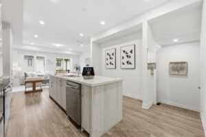 Contemporary kitchen with oversized quartz island, breakfast bar, stainless steel appliances and open layout.