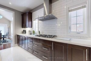 Designer kitchen with custom cabinetry, gas cooktop, and stylish tile backsplash.