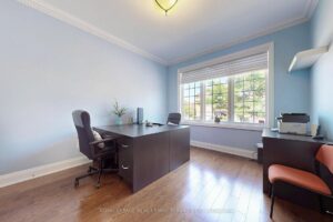 Main-floor home office with large window, hardwood flooring, and built-in workspace.