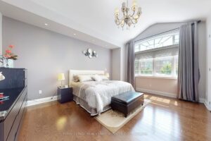 Bright bedroom with hardwood flooring, large picture window, and elegant neutral finishes.