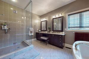 Luxury bathroom with glass walk-in shower, double vanity, and contemporary tile finishes.