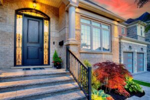 Twilight close-up of the covered front entrance with stone columns and custom front door.