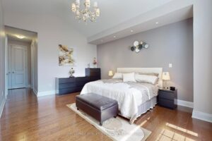Spacious primary bedroom with hardwood flooring, elegant furnishings, and large windows.