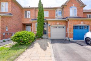 Two-storey brick townhouse with attached garage, interlock walkway, and landscaped front entrance.