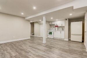 Open-concept finished basement with recreation area and kitchenette.