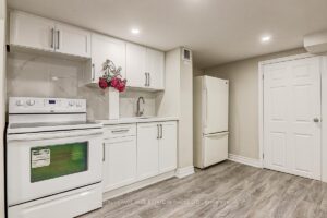 Basement kitchenette with white cabinetry, full-size appliances, and ample storage.