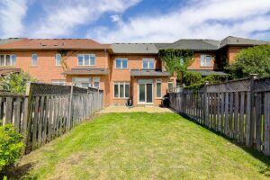 Fully fenced backyard with expansive lawn and rear view of the townhouse.
