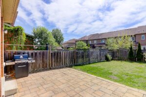 Private backyard featuring a stone patio, outdoor dining area, and fenced yard.