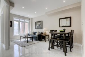 Open-concept living and dining area with large rear windows and modern tile flooring.