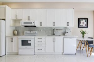 Modern kitchen with white cabinetry, quartz countertops, and stainless steel appliances.