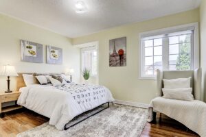 Bright primary bedroom with hardwood flooring, large window, and neutral décor.