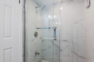 Contemporary bathroom with glass-enclosed shower and marble-look tile surround.