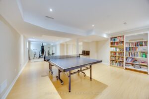 Finished recreation room at 2249 Glazebrook, Mississauga, featuring a ping pong table, fitness area, built-in bookshelves, and abundant open space.