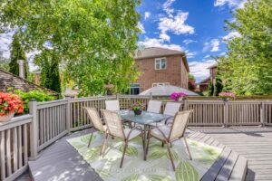 Private backyard entertaining area at 2249 Glazebrook, Mississauga, with elevated dining platform, mature trees, and flower planters.