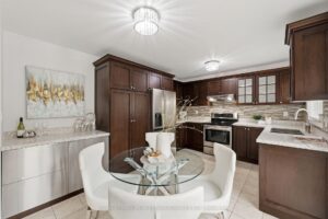 Bright breakfast area with adjoining kitchen with dark cabinetry.