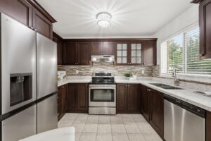 Functional kitchen with stainless steel appliances, ample cabinetry, and tile flooring.