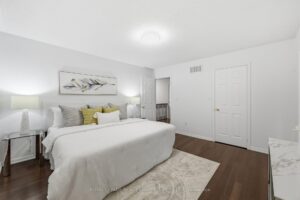 Spacious primary bedroom with hardwood flooring, large window, and neutral décor.