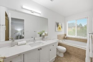 Primary ensuite with double vanity, soaker tub, separate shower, and bright finishes.