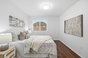 Bright secondary bedroom with hardwood flooring and large window.