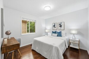 Comfortable bedroom with hardwood flooring and large window.