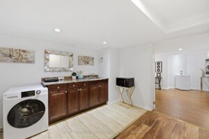Main-floor laundry room with washer, dryer, utility sink, and storage cabinetry.