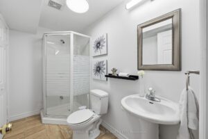 Basement bathroom with glass shower, pedestal sink, and modern finishes.